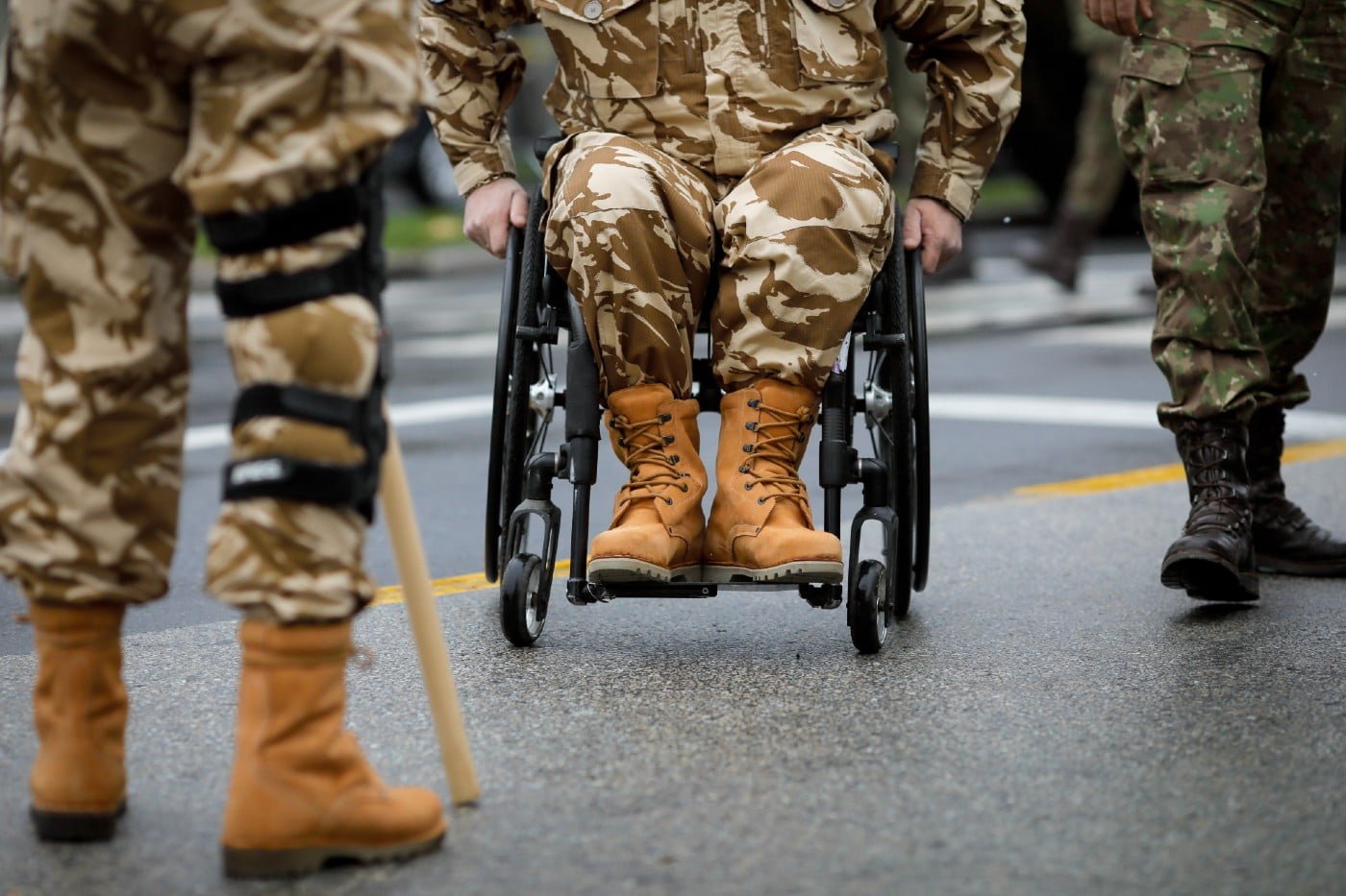 military personnel with one in a wheelchair and another with a knee brace and cane